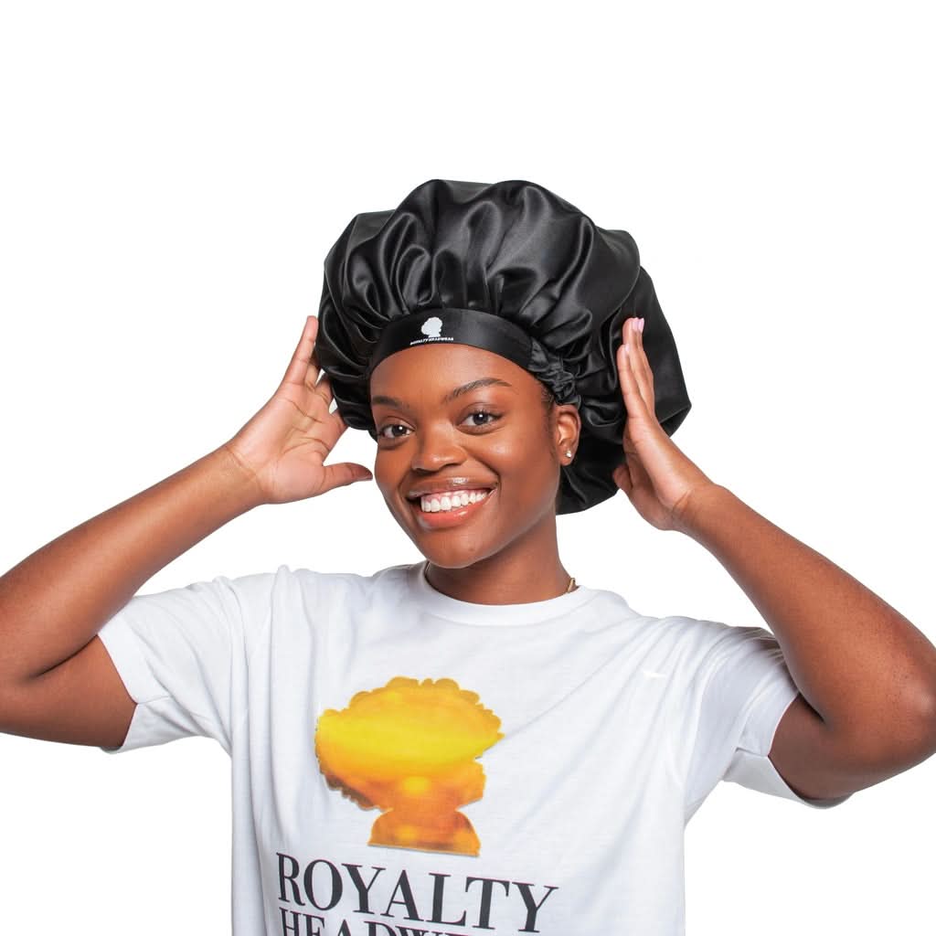 Ambassador Product black satin bonnet by Royalty Headwear, worn by smiling woman, ideal for protecting hair overnight or during styling.