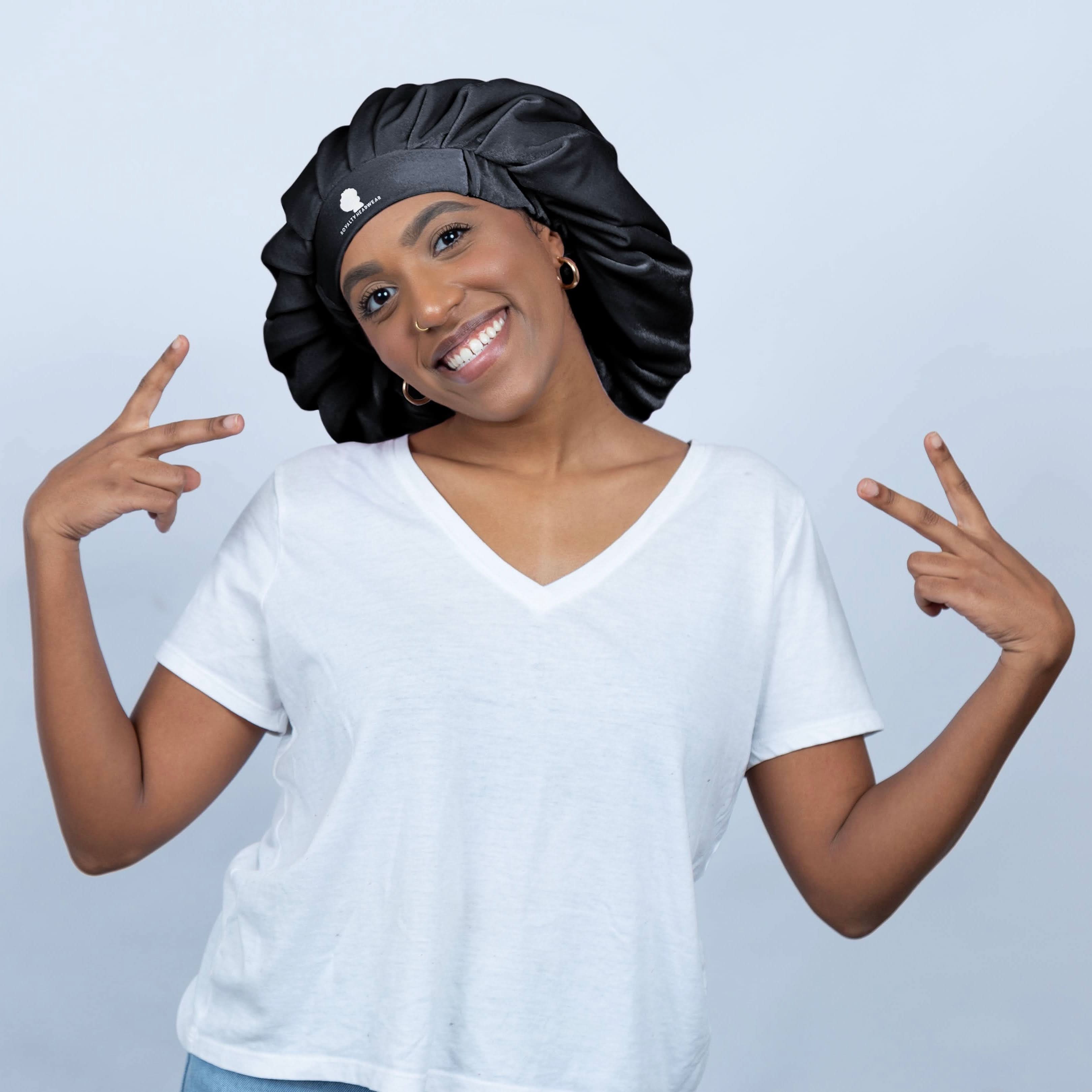 The Royalty Bonnet in sleek black satin, a jumbo silk bonnet for sleeping and maintaining hair moisture, modeled with a peace sign pose.